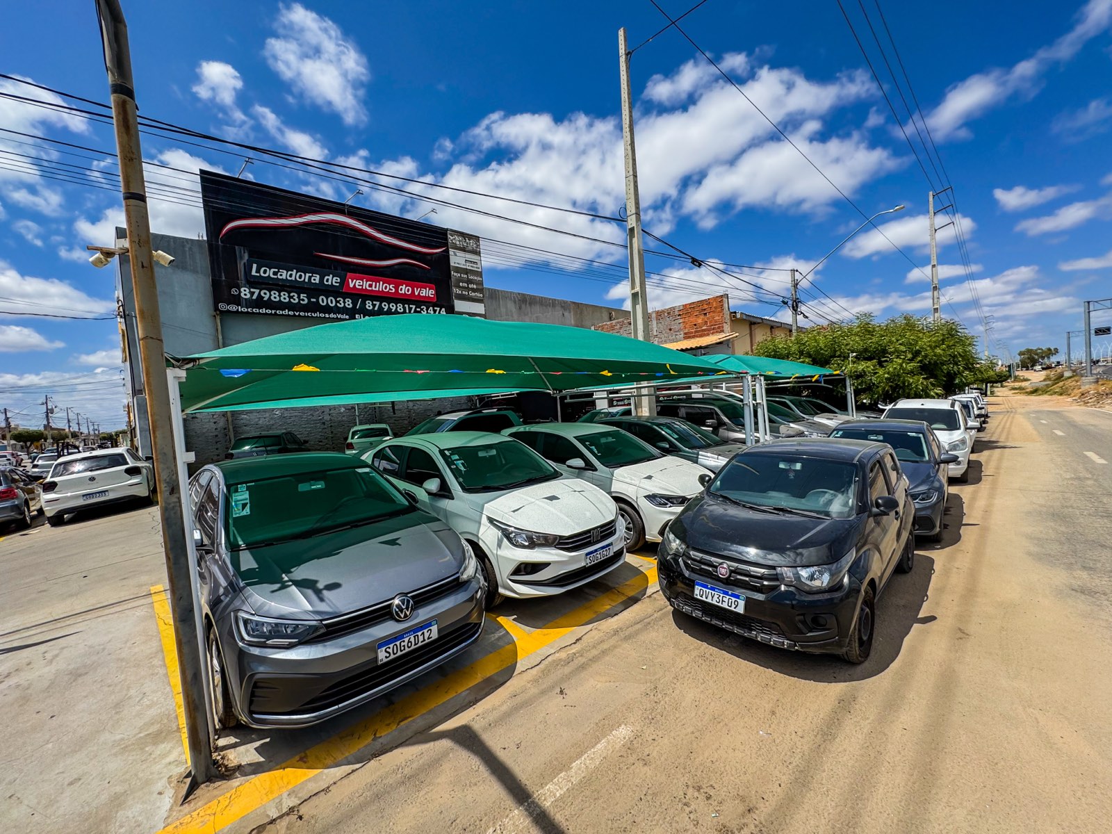 Carros da frota da Locadora do Vale estacionados sob a cobertura, em frente ao letreiro